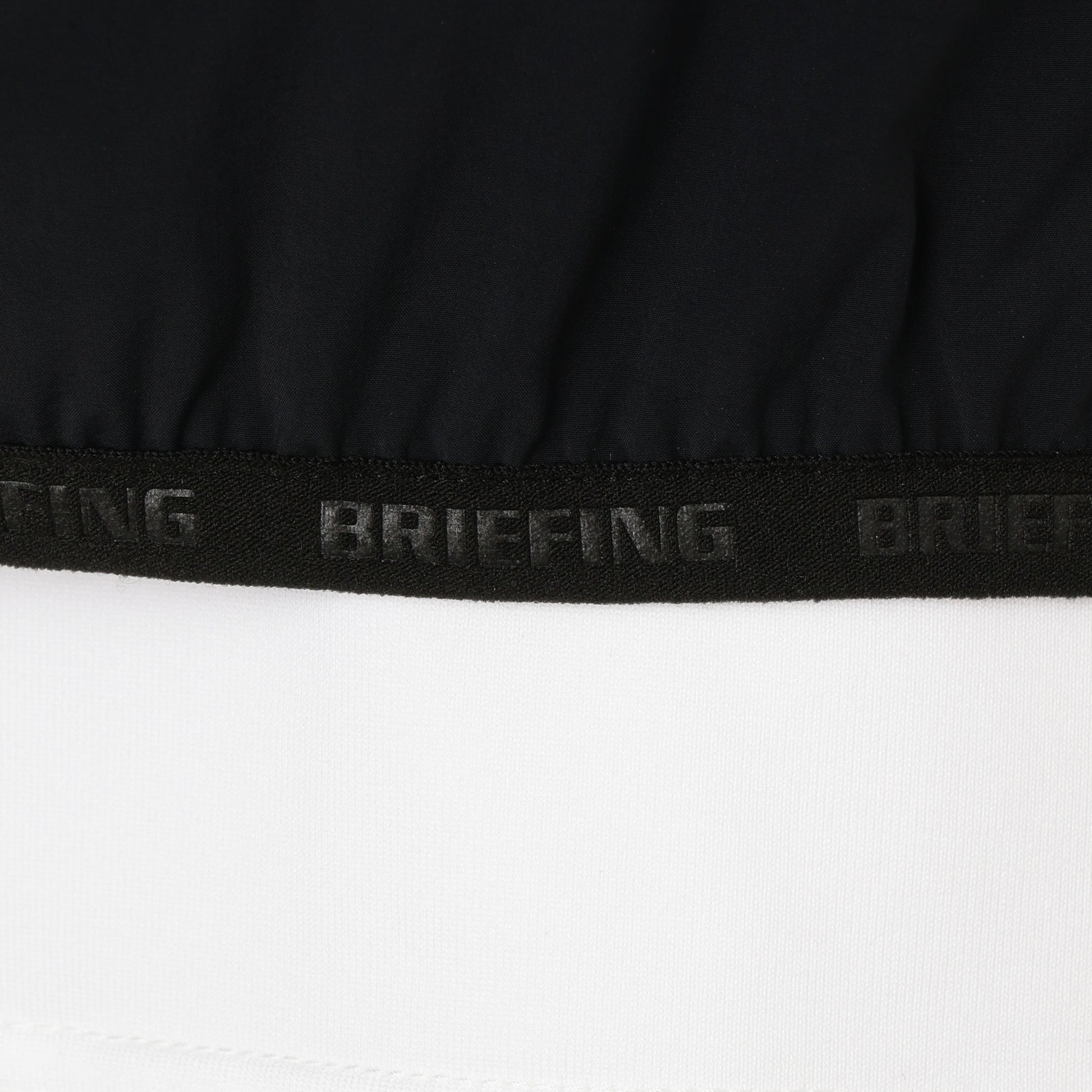 袖口、裾にあしらわれた、BRIEFINGのエンボスロゴ入りのパイピングテープ。