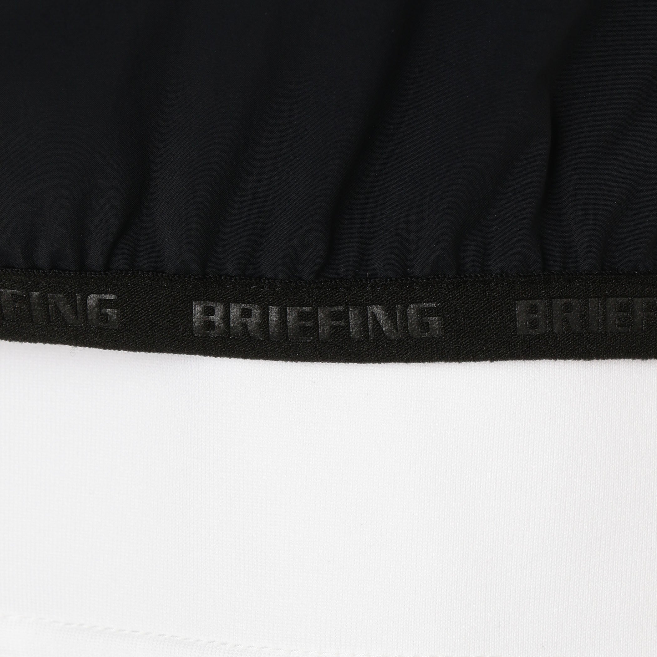 袖口、裾にあしらわれた、BRIEFINGのエンボスロゴ入りのパイピングテープ。