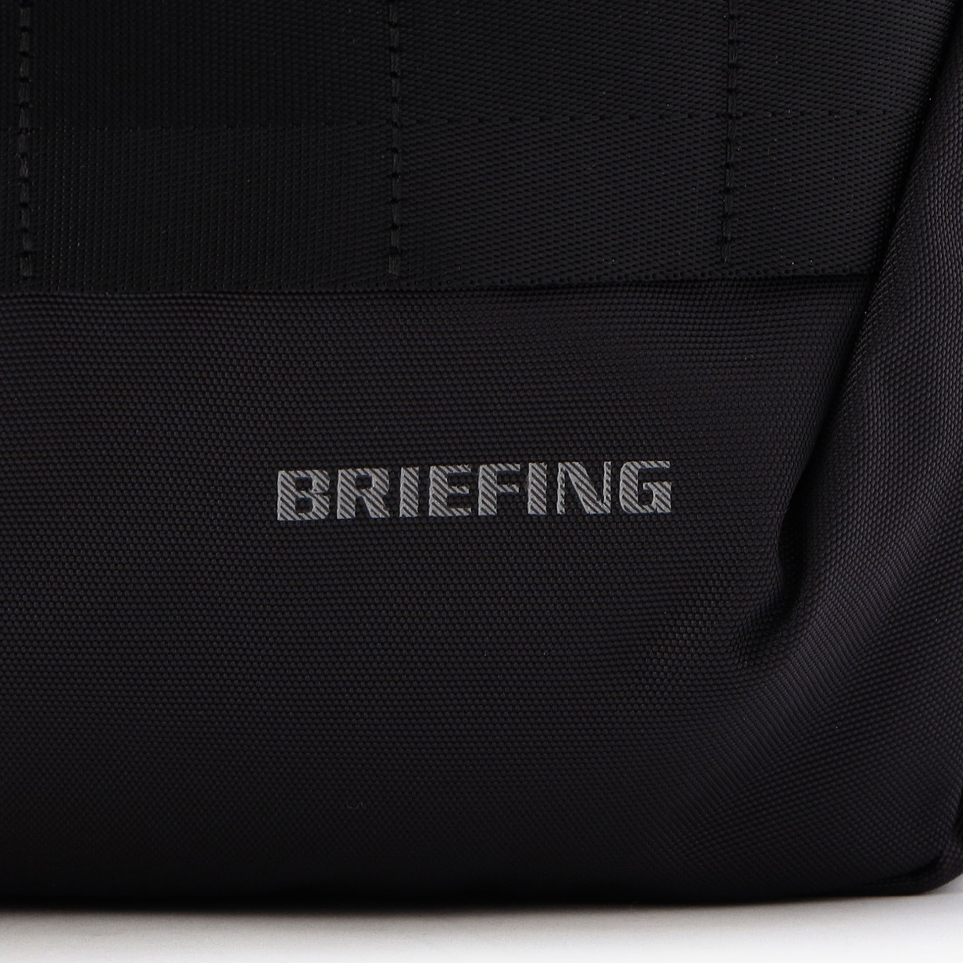 夜間時の移動に配慮し、フロントのBRIEFINGロゴとウェビングテープのステッチはリフレクター仕様に。