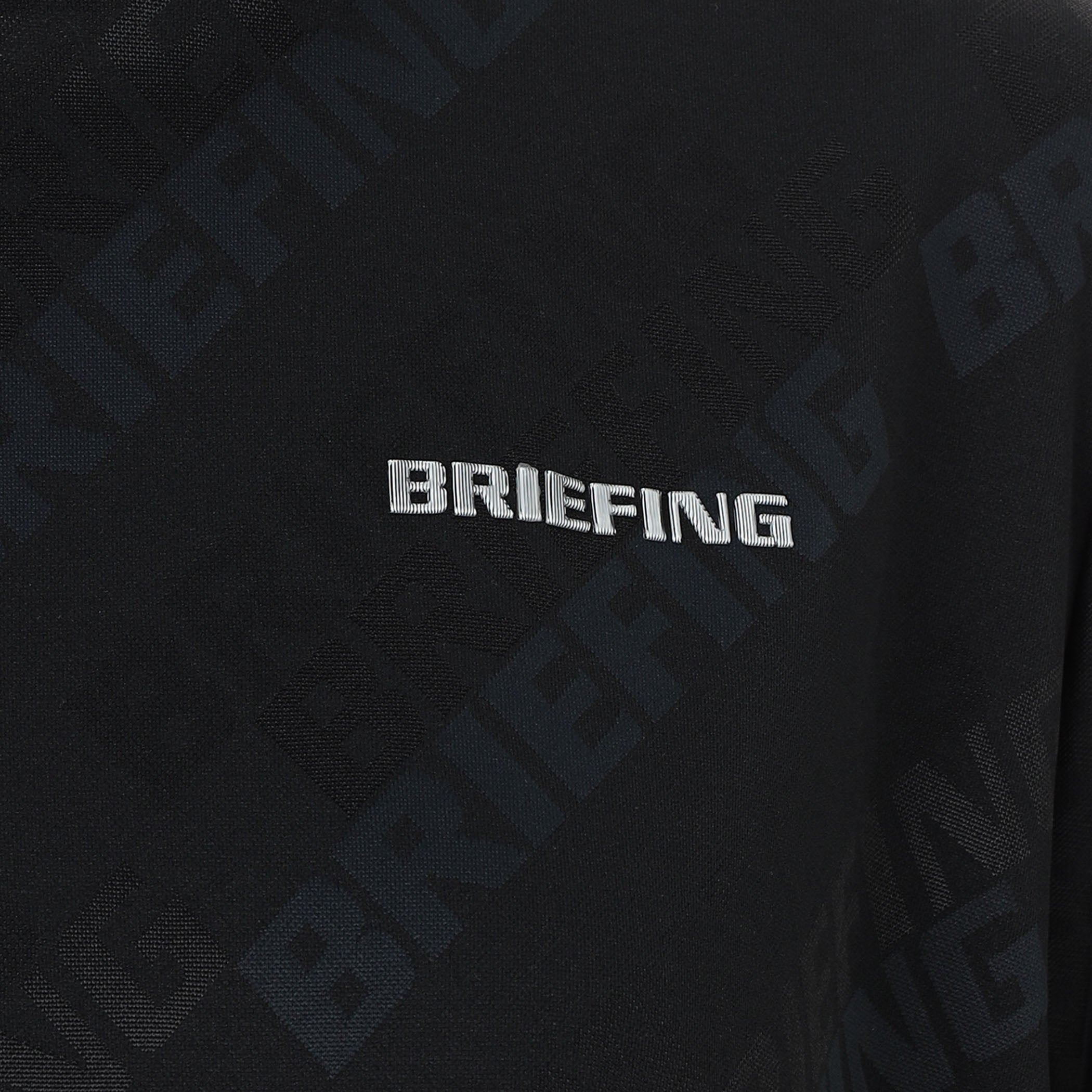 見る角度によって色味や光沢が変化して見えるBRIEFINGロゴを胸元に、Bマークロゴをバックネックに配置。