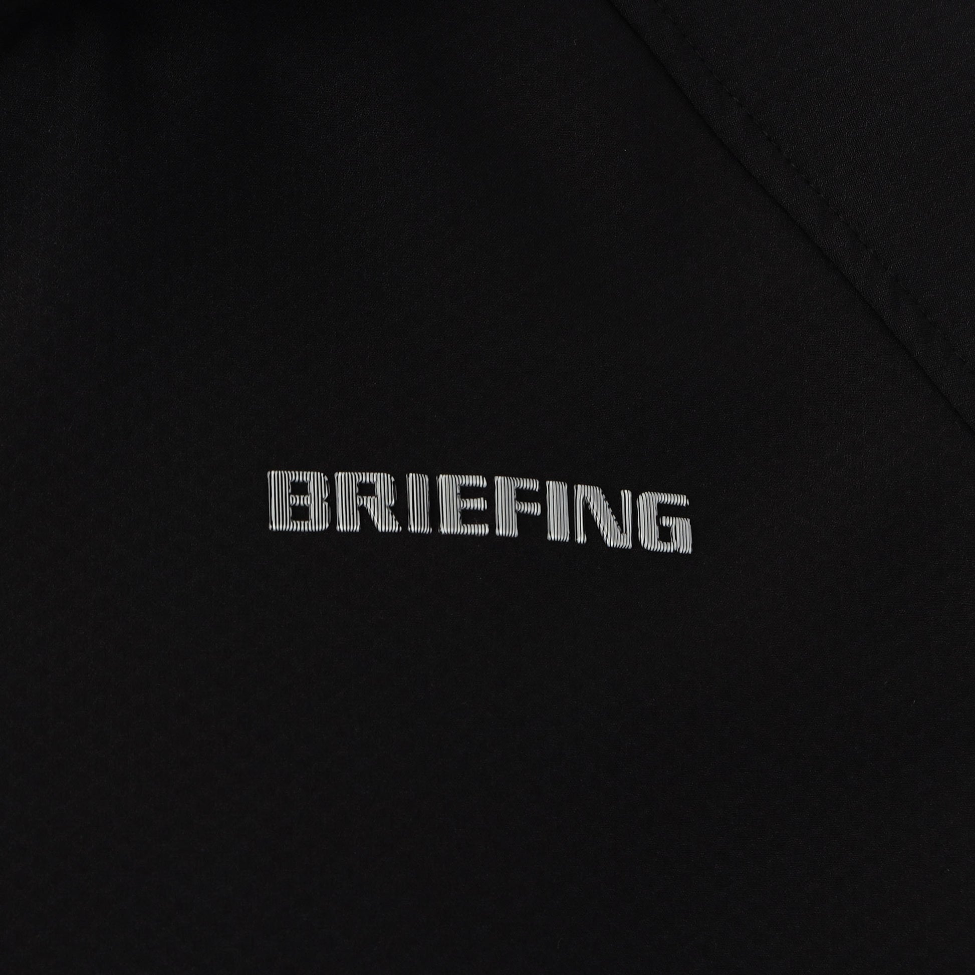 見る角度によって色味や光沢が変化して見えるBRIEFINGロゴを胸元に配置。