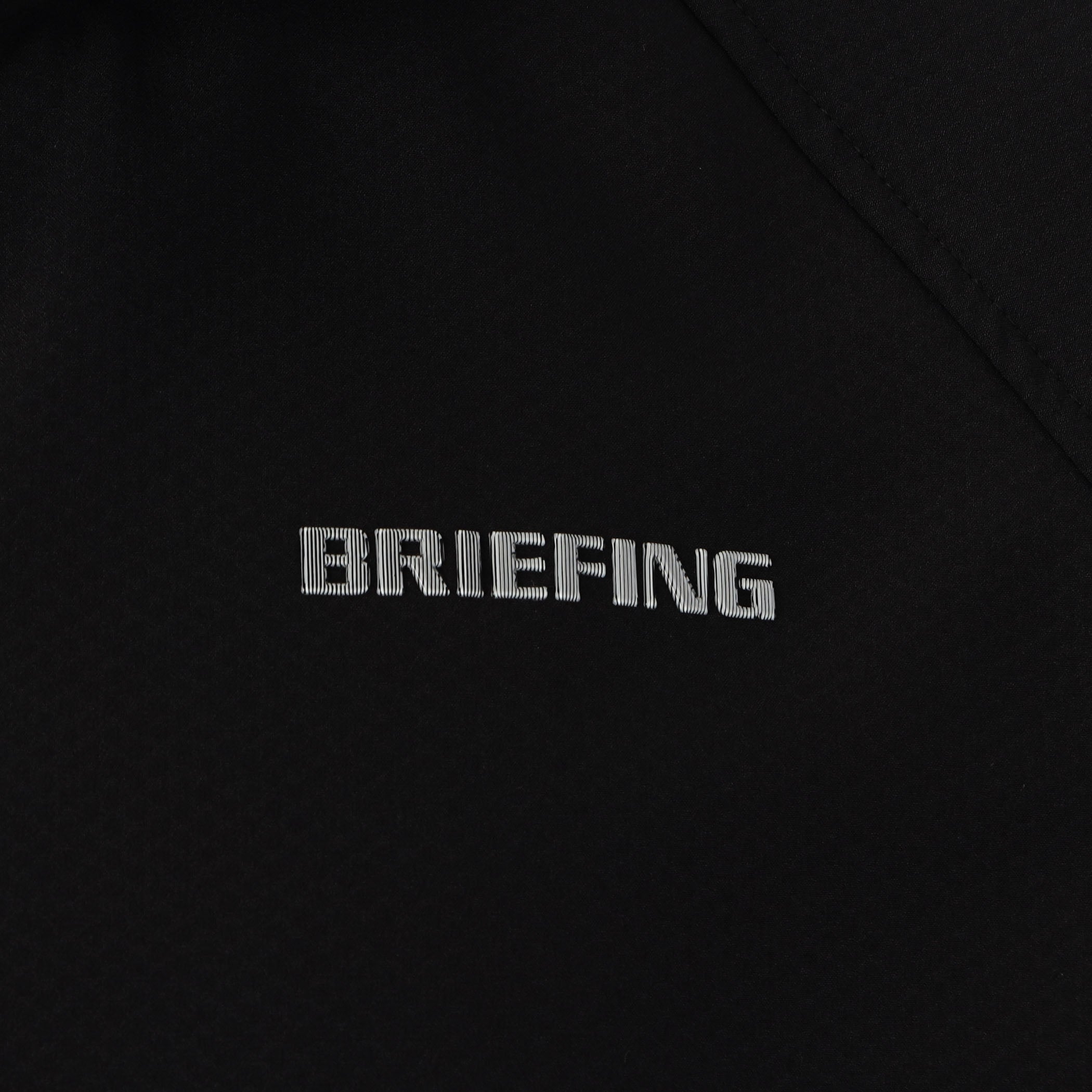 見る角度によって色味や光沢が変化して見えるBRIEFINGロゴを胸元に配置。